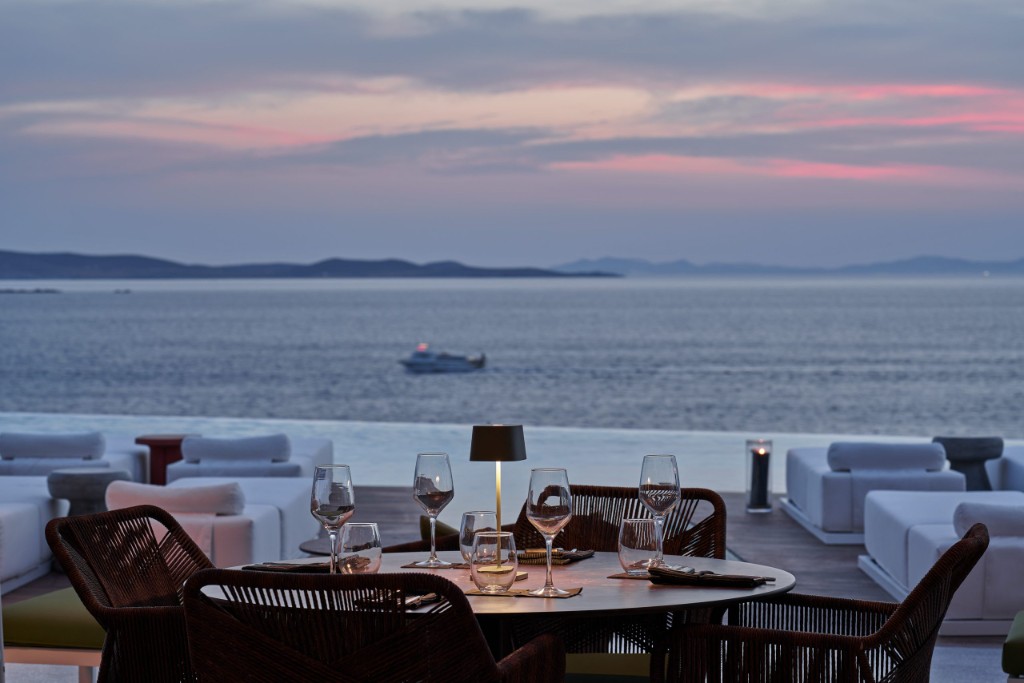 Narcissus at Kouros Hotel - poolside table at dusk with the Aegean Sea beyond